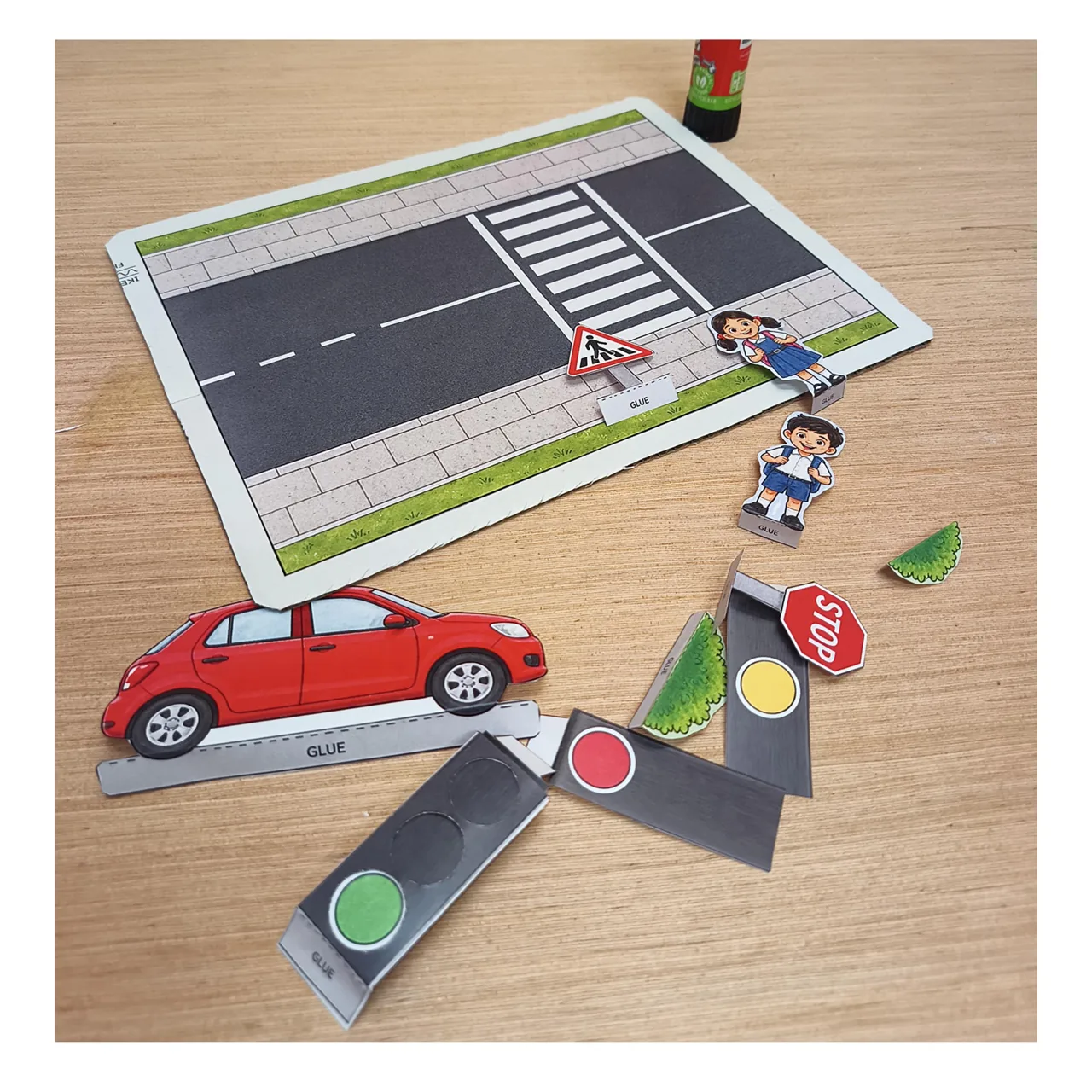 Cardboard road base and cut-out pieces ready to assemble into a road safety model.