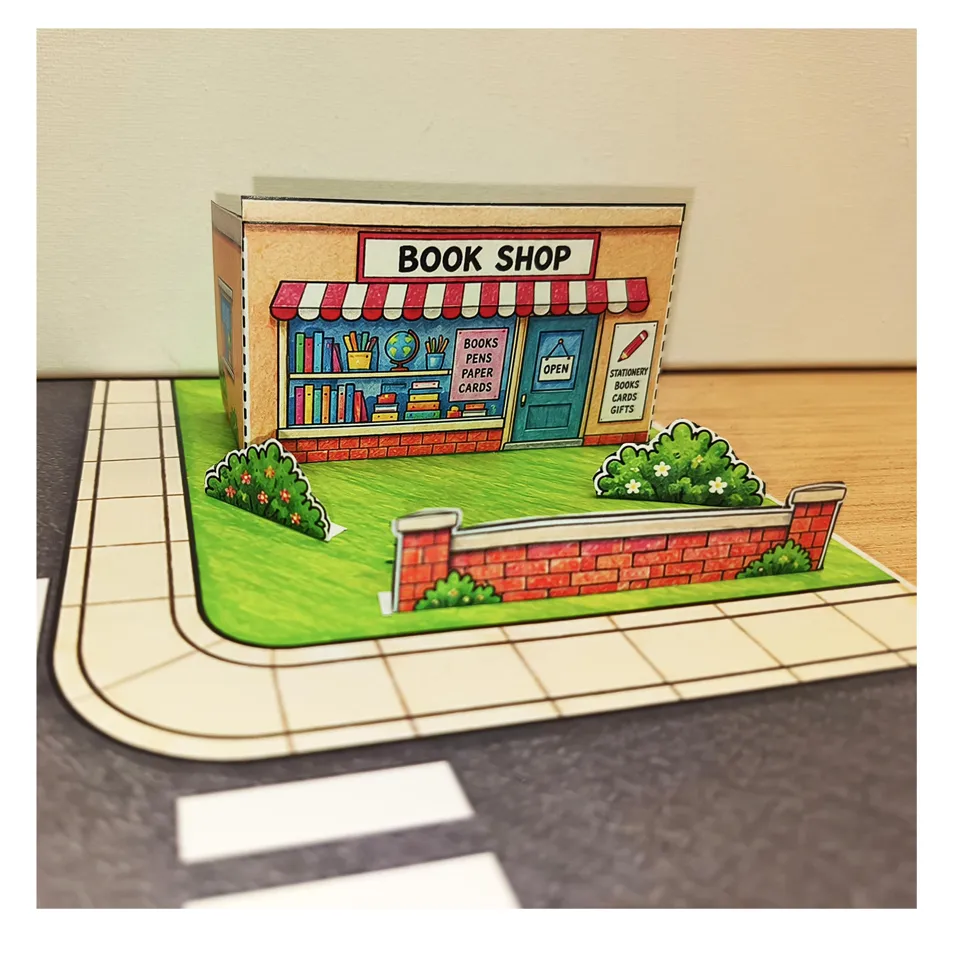 Assembled paper bookshop with a low wall and flower beds