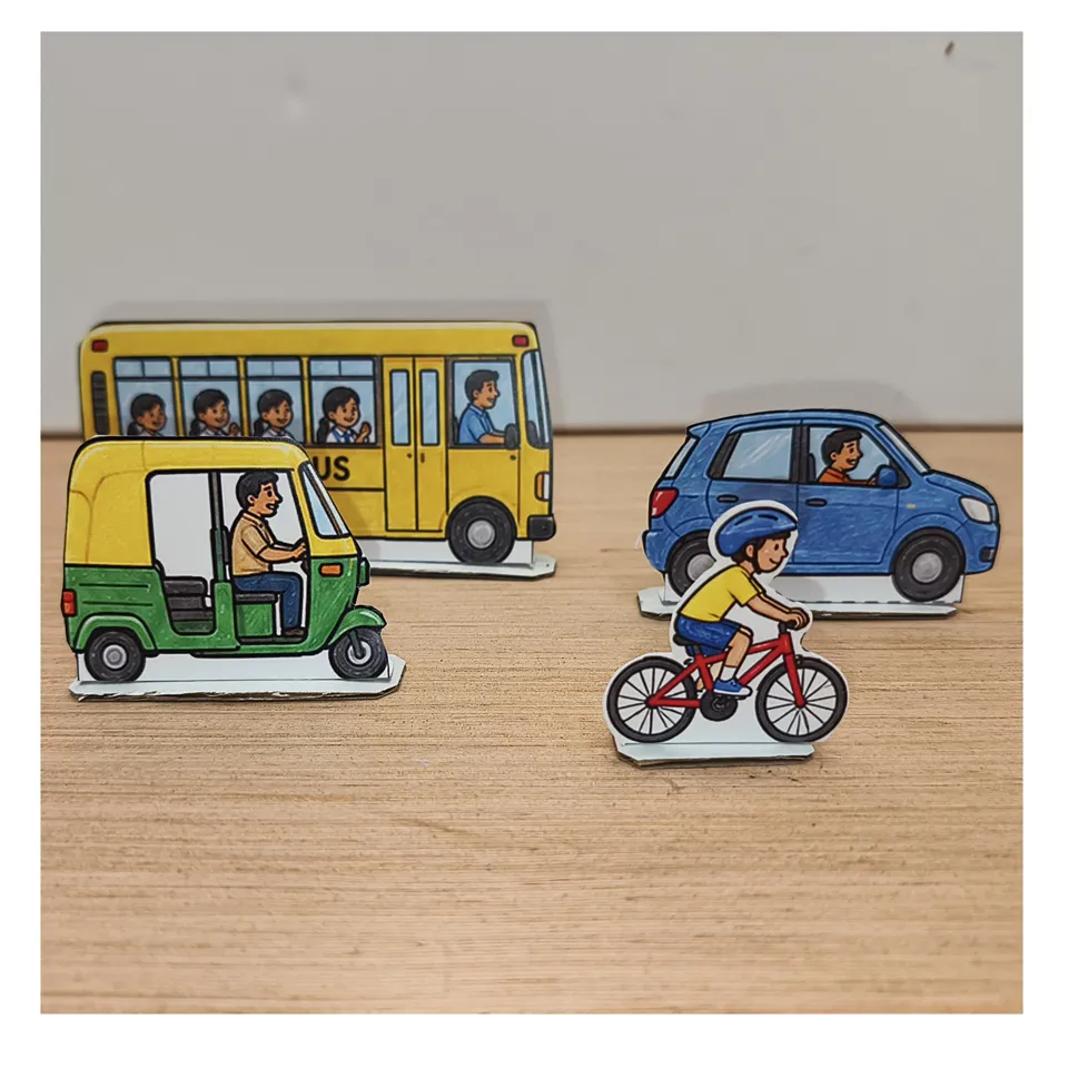 Paper school bus, auto-rickshaw, blue car and cyclist