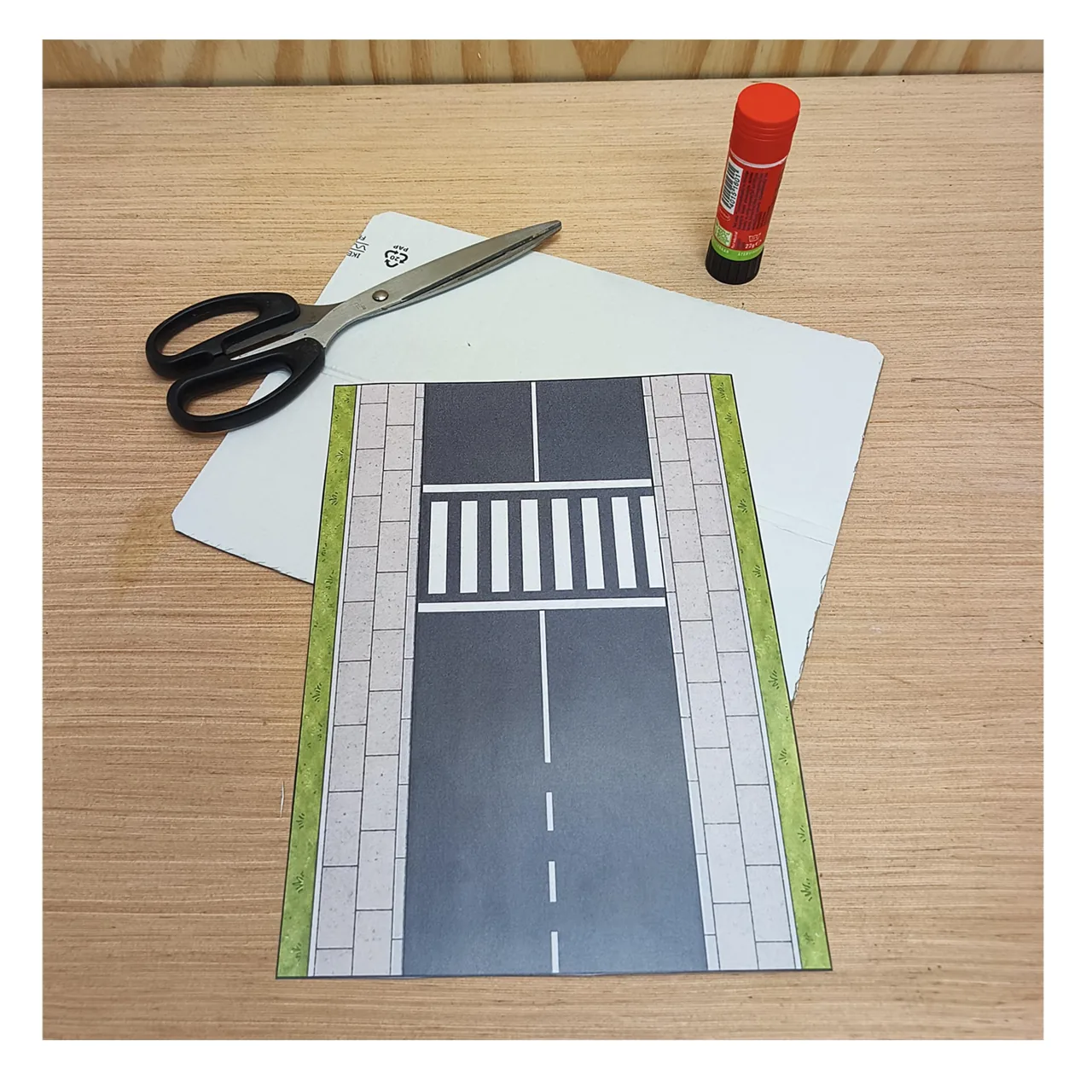 Printed zebra crossing road base with cardboard, scissors and glue, ready for mounting.